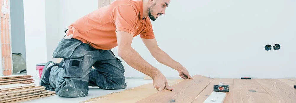 A flooring installer fits planks near the end of a job, the closeout stage where held retainage weighs heaviest on cash flow
