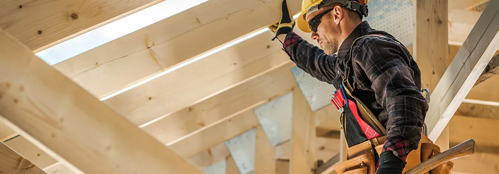 Carpenter setting roof framing on a wood-frame build, the most common type for residential construction