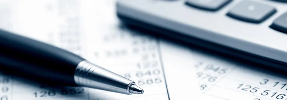 Contractor working through job budgets with a calculator and printed reports