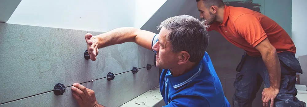 Renovation crew setting wall tile on a job priced from a clear scope of work