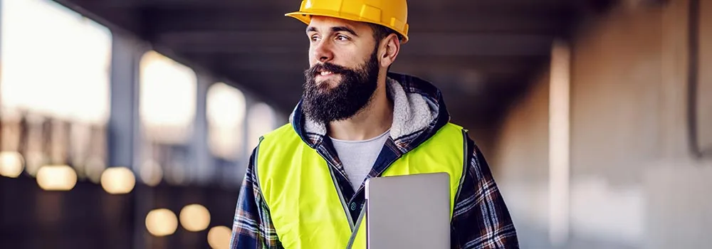 Site supervisor carrying a laptop to check crew hours between tasks