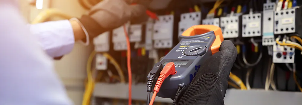 An electrician stands at the back of his work van between jobs; drive time and job switching are where untracked minutes pile up